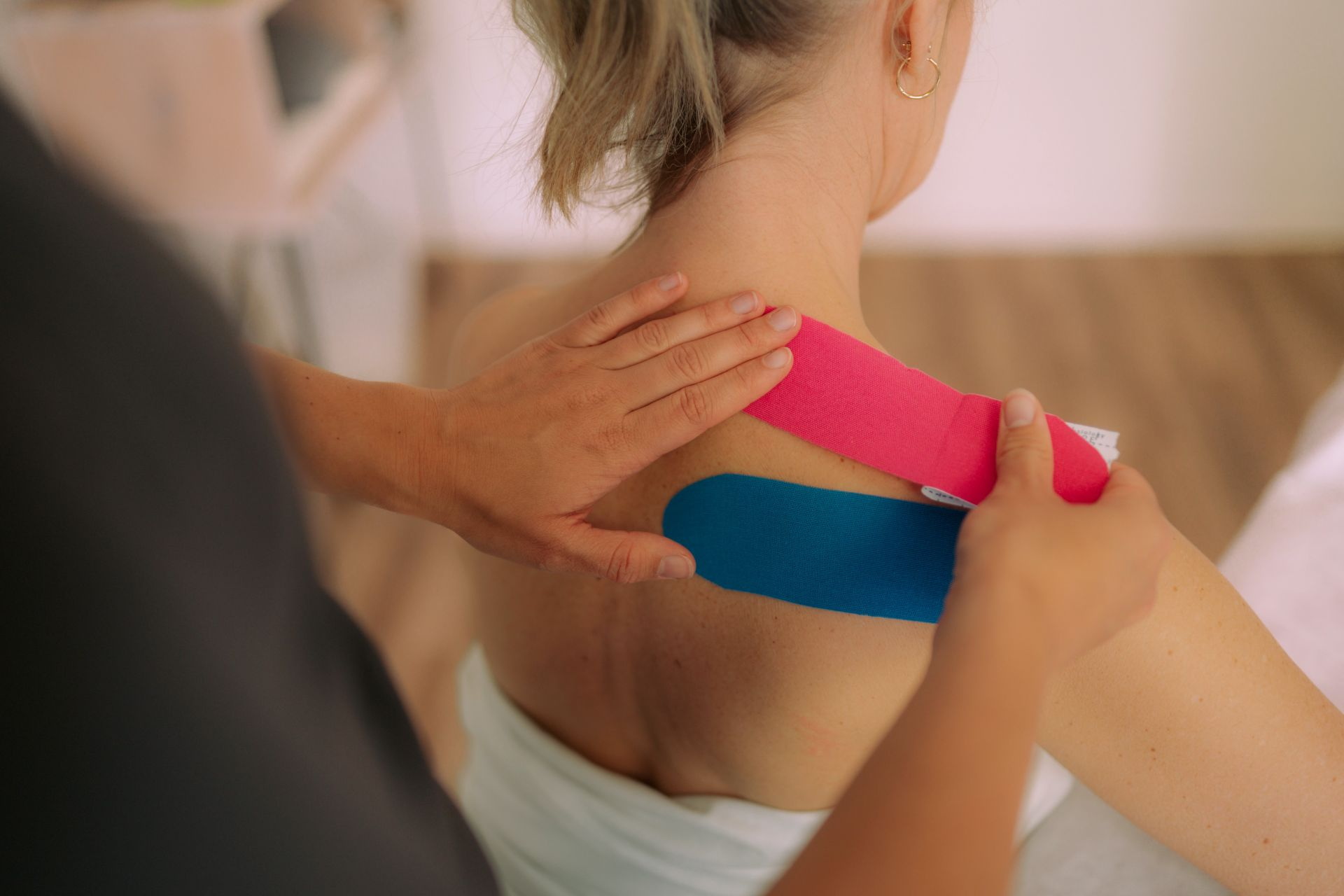 Kinesiotaping mit grünem und rotem Tape am Oberarm eines Patienten